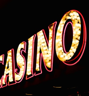 Brightly illuminated letters spell out 'CASINO' with glowing yellow bulbs and red outlines against a dark background.
